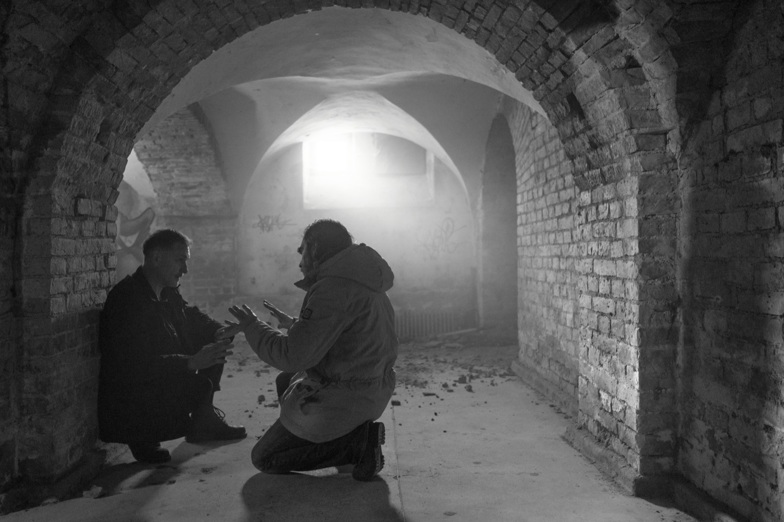 Still from the video: figures in a misty stone tunnel