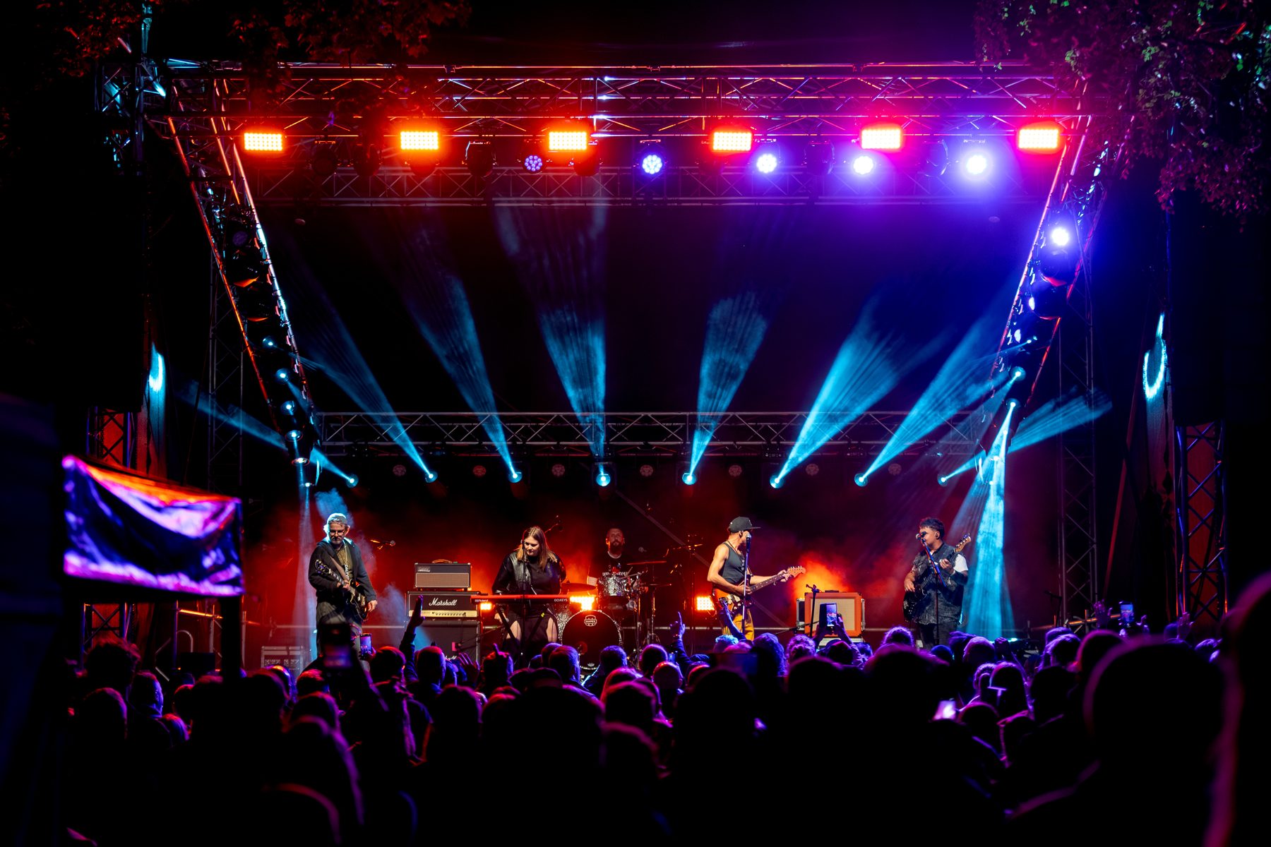 Band on stage under blue and red lights in front of the crowd