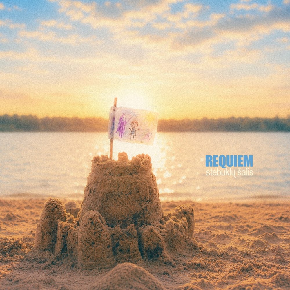 Stebuklų šalis single cover: a sandcastle with a flag at sunset
